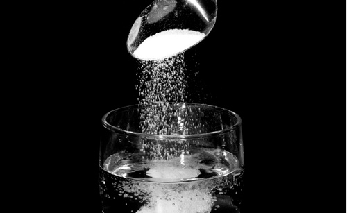 salt pouring into a glass of water