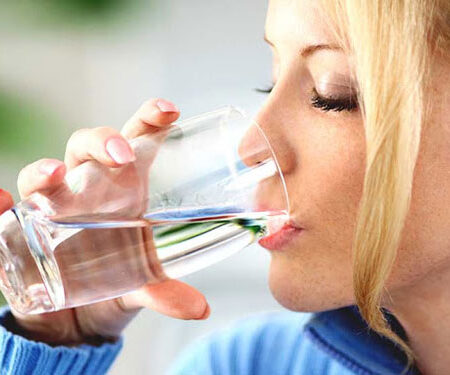 Closeup of adult blond woman drinking water.