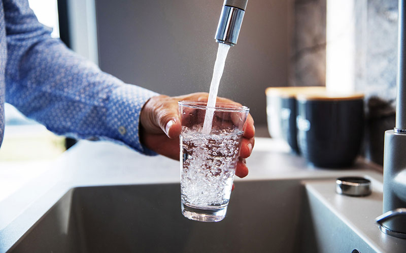 glass of water being filled up in a sink