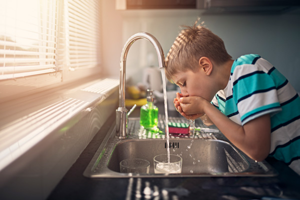 kid drinking from faucet