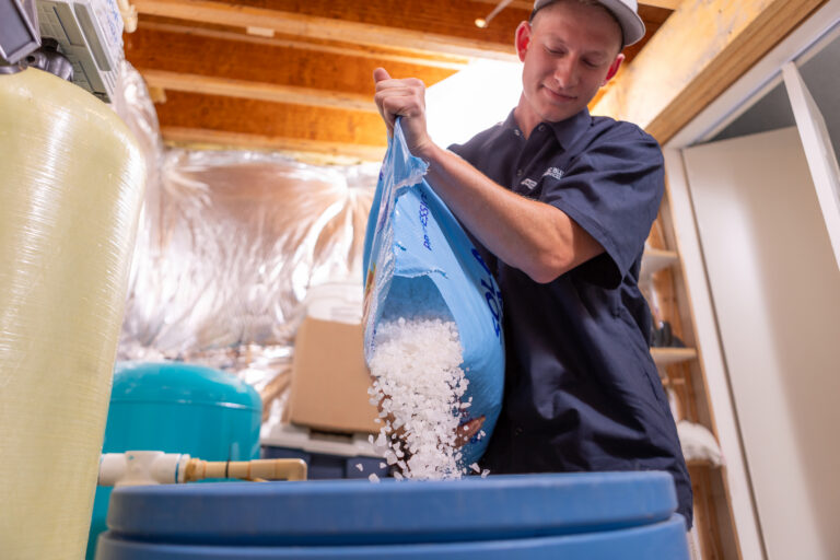 Atlantic Blue technician filling a water softener with salt during salt delivery